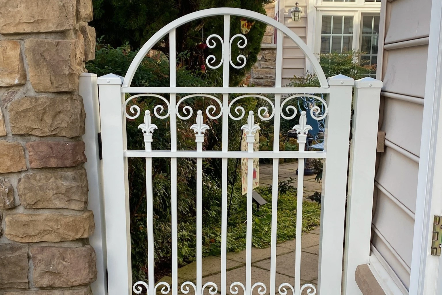 Photo of a white decorative metal gate to an outdoor sitting area 