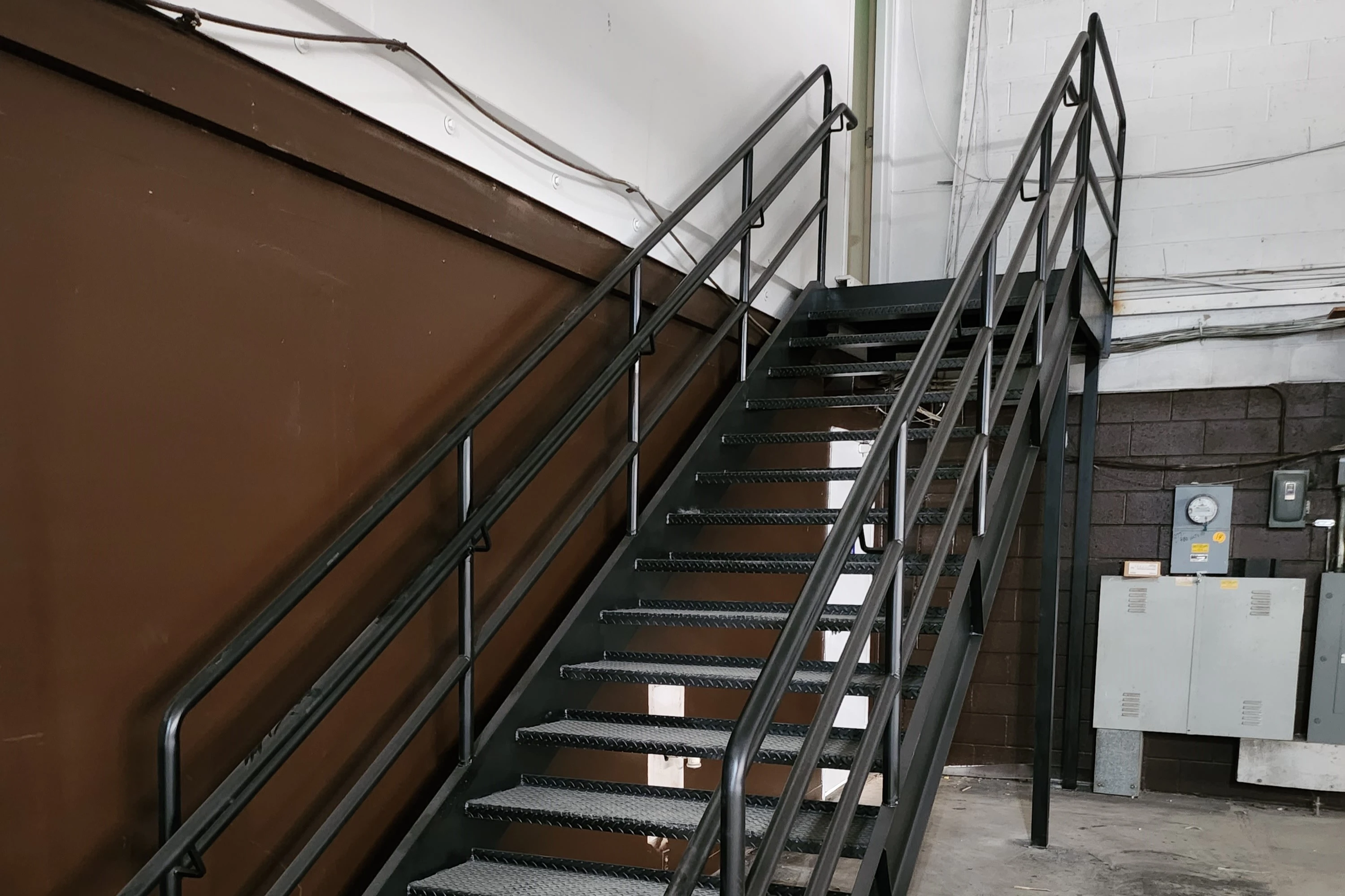 Photo of black metal staircase in industrial setting, front view